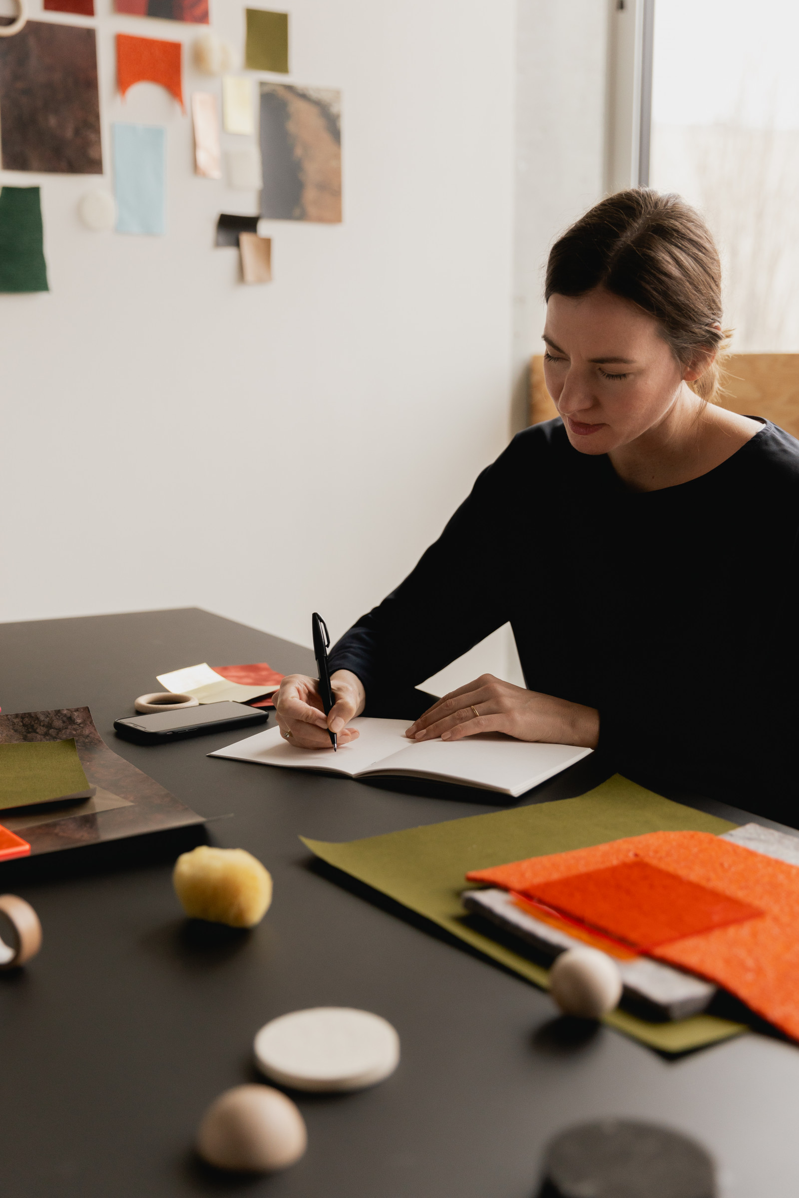 Designer writing beside colorful material samples
