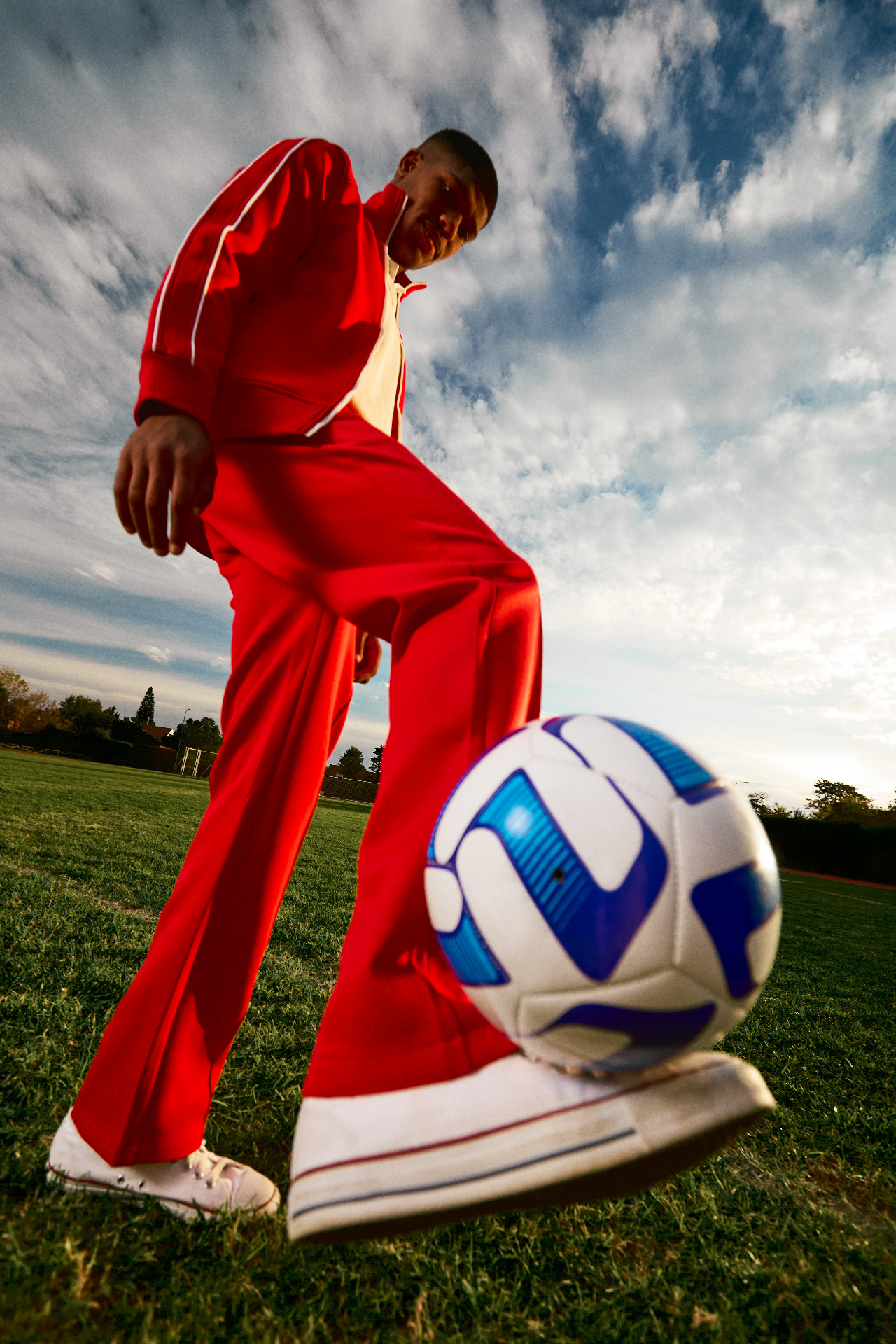 Football player in a red tracksuit stepping toward a ball